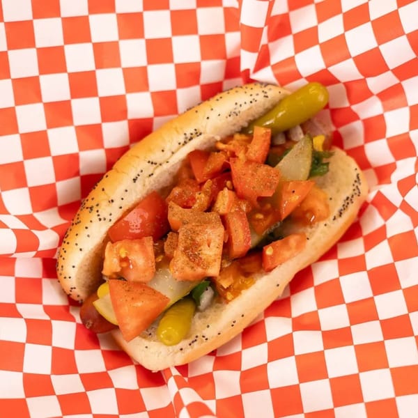 Mel's Hot Dog with diced tomatoes, pickles, and spices in a poppy seed bun.