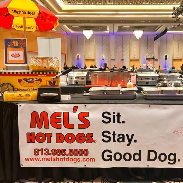 A Mel's Hot Dogs stand with a Vienna Beef umbrella, hot dog cart, and food warmers.