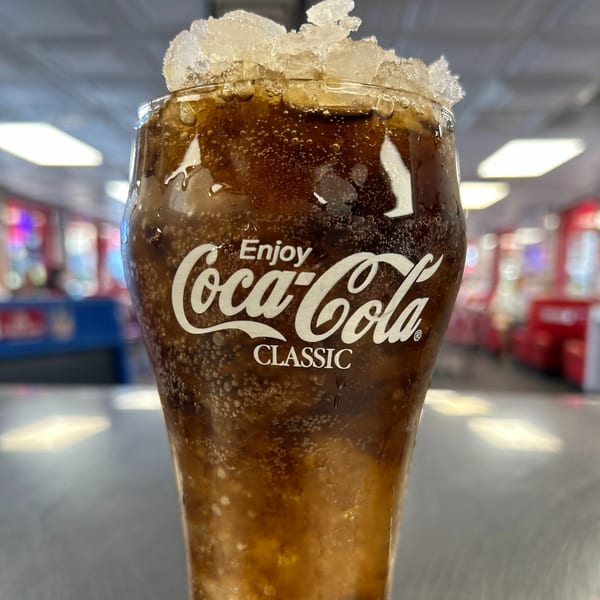 Close-up of a Coca-Cola Classic drink with ice, bubbles, and condensation, at Mel's Hot Dogs.